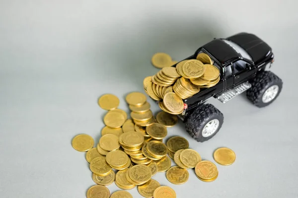 Miniature car pickup truck with stacks of coins on grey backgrou