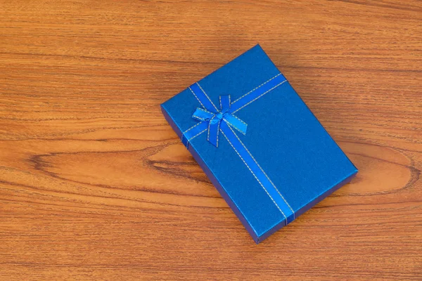 Blue box with ribbon bow on wooden table with copy space for sea