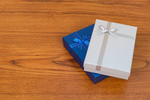 Blue and white box with ribbon bow on wooden table with copy spa