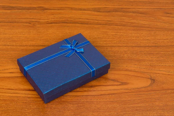 Blue box with ribbon bow on wooden table with copy space for sea