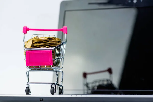Stack av mynt i shopping cart eller stormarknad vagn med lapt — Stockfoto