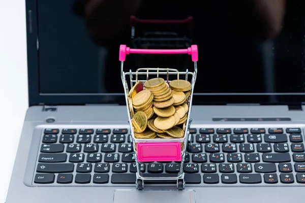 Stack di monete nel carrello della spesa o carrello del supermercato con lapt — Foto Stock