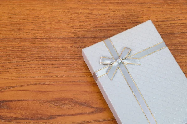 Blue white box with ribbon bow on wooden table with copy space f