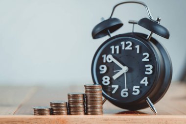 Çalar saat ve para yığınları adım çalışma masasında zaman için 