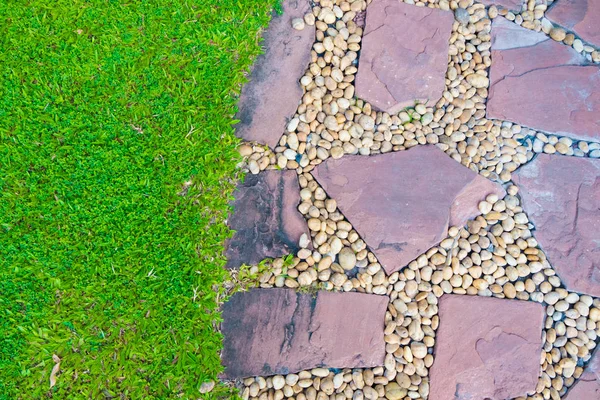 Campo in erba verde con sentiero in pietra e piccola decorazione rocciosa . — Foto Stock