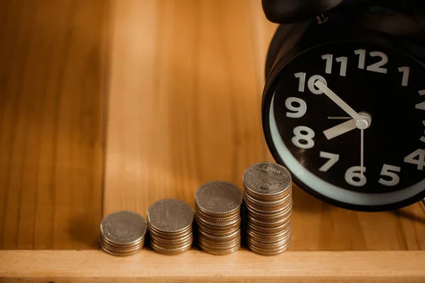 Wekker en stap van munten stapels op de werktafel, tijd voor — Stockfoto