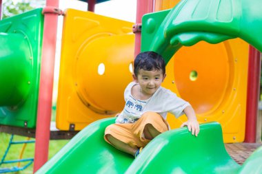 Küçük Asyalı Çocuk Bahçesi sunli altında slayt oynayan
