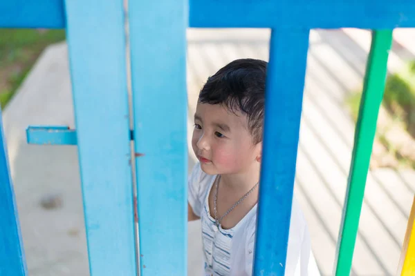 Smile Asian kid behind the colorful fence at playground in summe — Stock Photo, Image