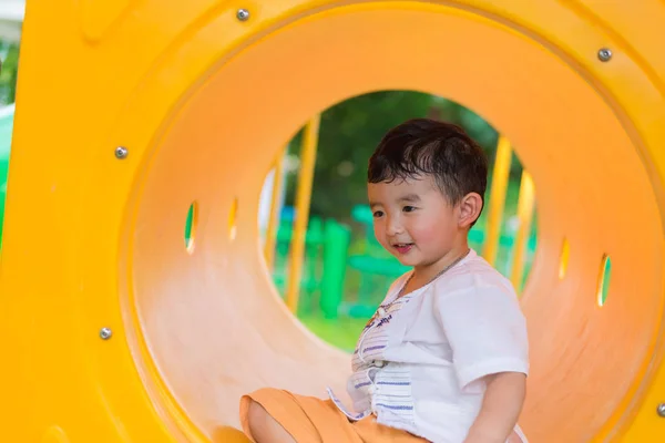 Милый азиатский мальчик играет и улыбается в желтом туннеле на плей-офф — стоковое фото