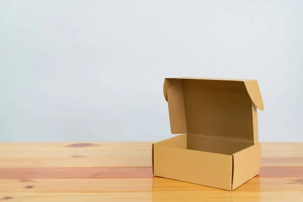 Caixa de papelão marrom vazia na mesa de madeira com espaço de cópia . — Fotografia de Stock