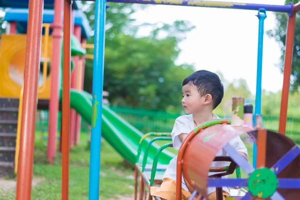 Sad little Asian kid at the playground under the sunlight in sum