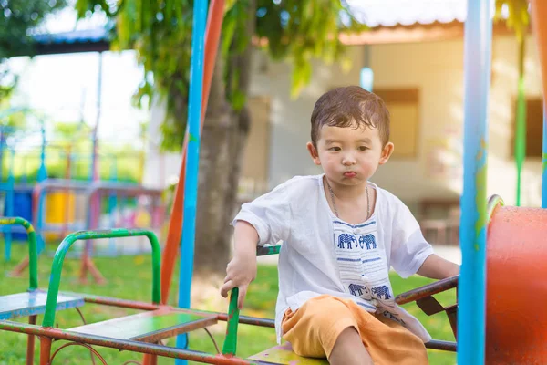 Young Asian boy play a iron train swinging at the playground und — Stock Photo, Image