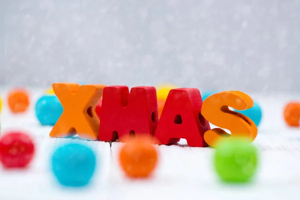 Vánoční barevné dřevěné text na bílý dřevěný stůl s vánoční de — Stock fotografie