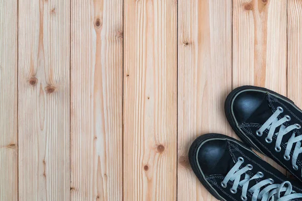 Kopya alanı ile ahşap arka plan üzerinde siyah spor ayakkabı. Üstten Görünüm. H