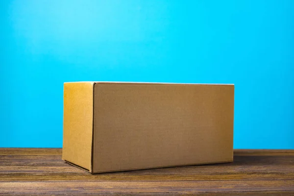 Caja de cartón marrón cerrada vacía para maqueta en tabl de madera oscura — Foto de Stock