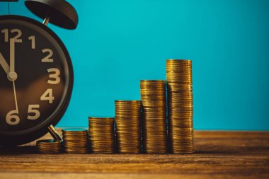 Çalar saat ve para yığınları adım çalışma masasında zaman için 