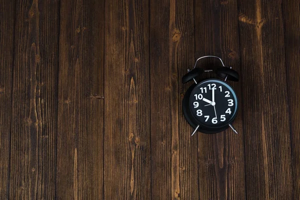 Relógio de alarme preto vintage na mesa de madeira escura, tempo e prazo — Fotografia de Stock