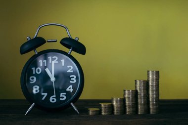 Çalar saat ve para yığınları adım çalışma masasında zaman için 
