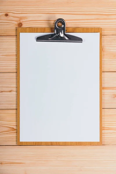 Portapapeles con hoja de papel blanco en blanco sobre tabla de madera vista superior wi — Foto de Stock
