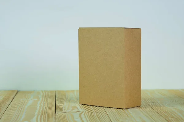 Caixa de papelão marrom fechada vazia para simular na mesa de madeira — Fotografia de Stock