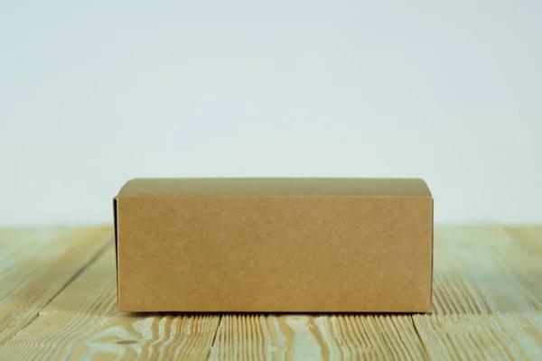 Caja de cartón marrón cerrada vacía para maqueta en la mesa de madera — Foto de Stock
