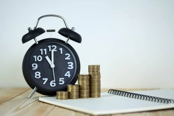 Pasos de pila de monedas con reloj despertador vintage y pluma, portátil —  Fotos de Stock