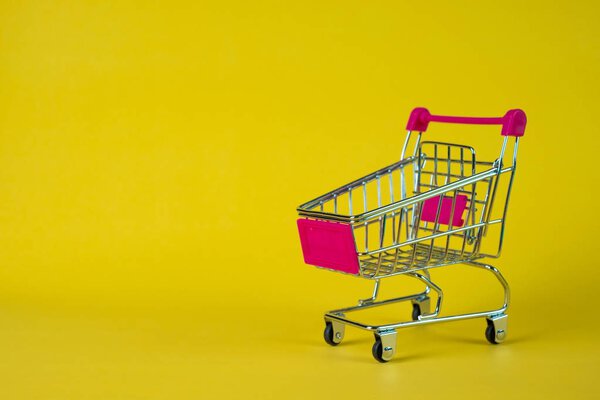 Shopping cart or supermarket trolley on yellow background, busin