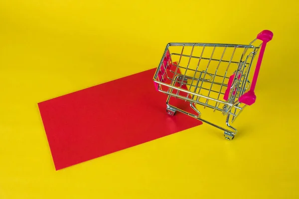 Carro de la compra o carro del supermercado y sobre rojo en blanco en ye — Foto de Stock