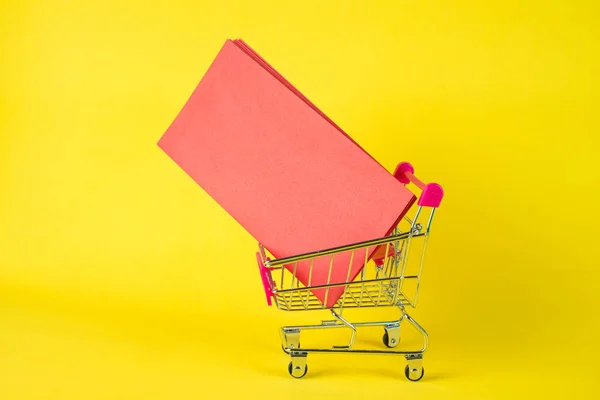 Carro de la compra o carro del supermercado y sobre rojo en blanco en ye — Foto de Stock