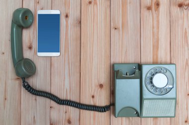 Retro döner telefon veya vintage telefon kablosu ve yeni cep telefonu ile veya ahşap masa, kopya alanı ile üstten görünüm, teknoloji ilerleme kavramı akıllı telefon.