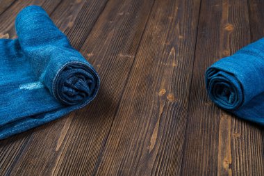 Frayed kot pantolon ya da kot denim koleksiyonu kaba koyu ahşap masa arka plan kopya alanı, eski moda stil kavramı ile rulo.