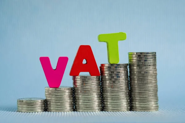 VAT (Value Added Tax) concept. Word VAT alphabet made from wood with stack of coin, business and financial concept idea.