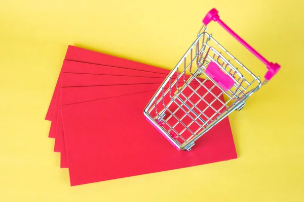 ショッピング カートやスーパー マーケットのトロリーと空白の赤黄色の封筒のためのスペースと背景追加テキスト 中国の新年およびショッピングのコンセプト アイデア — ストック写真