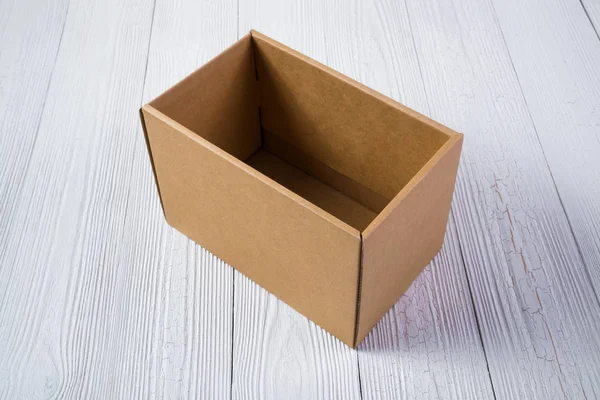 Pacchetto vuoto scatola di cartone marrone o vassoio su un tavolo di legno luminoso — Foto Stock