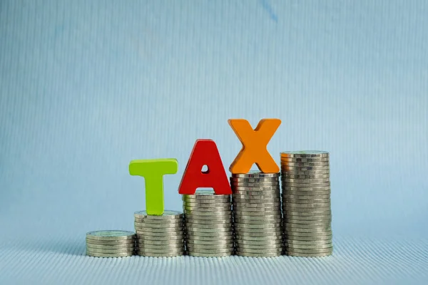 Concepto de impuestos. Alfabeto Word TAX hecho de madera con pila de moneda —  Fotos de Stock