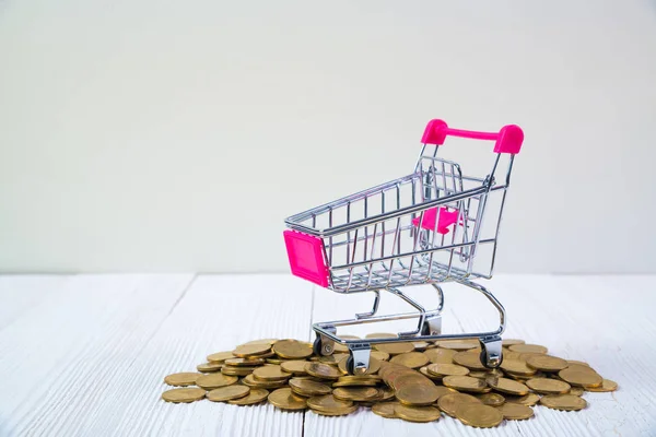 Grămezi de monede și coș de cumpărături sau cărucior de supermarket pe alb — Fotografie, imagine de stoc