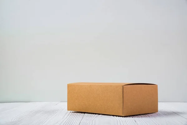 Pacote vazio caixa de papelão marrom ou bandeja em mesa de madeira brilhante — Fotografia de Stock