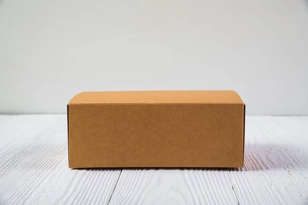 Paquete vacío caja de cartón marrón o bandeja en mesa de madera brillante — Foto de Stock