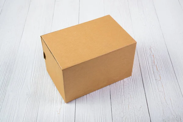 Pusty pakiet brązowy karton lub taca na jasny drewniany stół — Zdjęcie stockowe