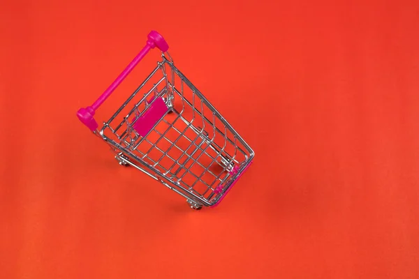 Carro de la compra o carrito de supermercado sobre fondo rojo, negocio — Foto de Stock