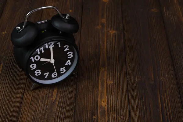 Relógio de alarme preto vintage na mesa de madeira escura, tempo e prazo — Fotografia de Stock