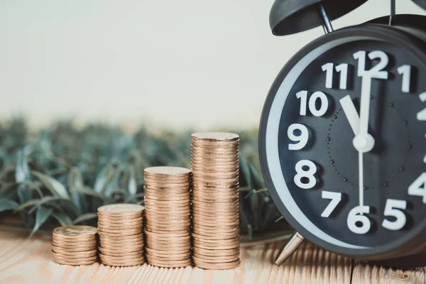 Steps of coins stack with vintage alarm clock on wooden working — Stock Photo, Image