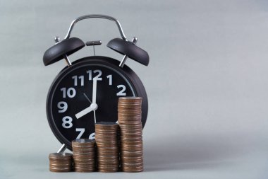 Çalar saat ve para yığınları adım çalışma masasında zaman için 