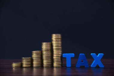 Vergi kavramı. Vergi alfabesi koyu arka planda para yığını ile,