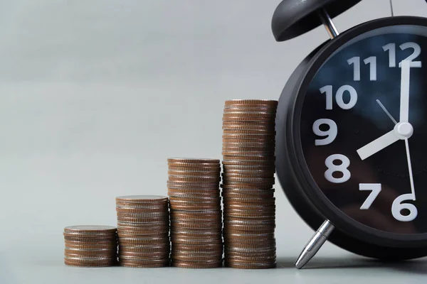 Relógio de alarme e passo de pilhas de moedas na mesa de trabalho, tempo para — Fotografia de Stock