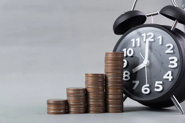 Reloj despertador y paso de las pilas de monedas en la mesa de trabajo, tiempo para — Foto de Stock