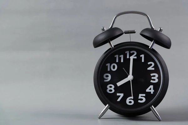 Relógio de alarme vintage de cor preta no fundo cinza, tempo de despertar — Fotografia de Stock