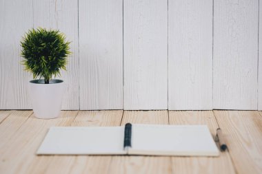 Küçük dekoratif ağacında beyaz vazo ve notebook wo üzerinde kalem ile