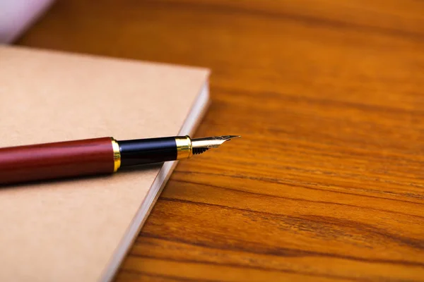 Pluma estilográfica o pluma de tinta con papel cuaderno en madera de trabajo ta — Foto de Stock