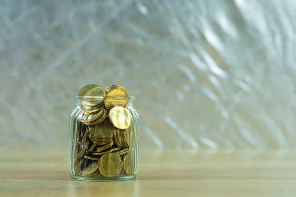 Moneda de dinero en el frasco de vidrio en la mesa, para el ahorro y la aleta bancaria — Foto de Stock